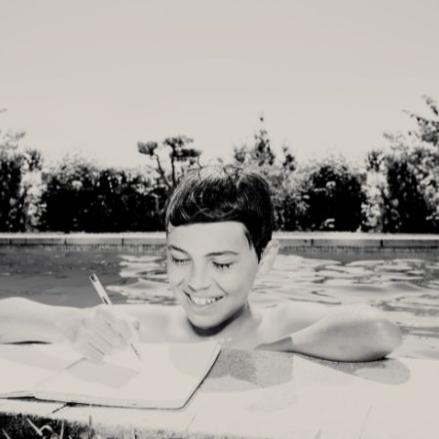 Niño haciendo deberes en una piscina