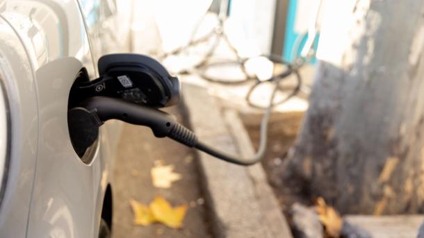 Un coche enchufado en un punto de carga - Imagen de archivo.