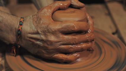 Manos haciendo una pieza de cerámica en un torno de alfarero