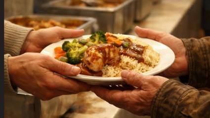 Unas manos entregan un plato de comida a otras manos que lo reciben