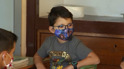 Niño sentando en su pupitre en el primer día de clase durante la pandemia