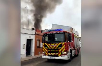 Vivienda incendiada en Montijo junto a un camión de los bomberos que trabaja en su extinción