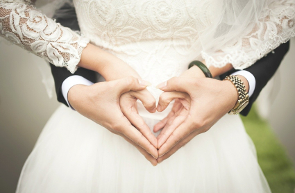 Dos novios realizan el gesto del corazón con sus manos