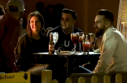 Jóvenes tomando una bebida en la terraza de un bar de noche