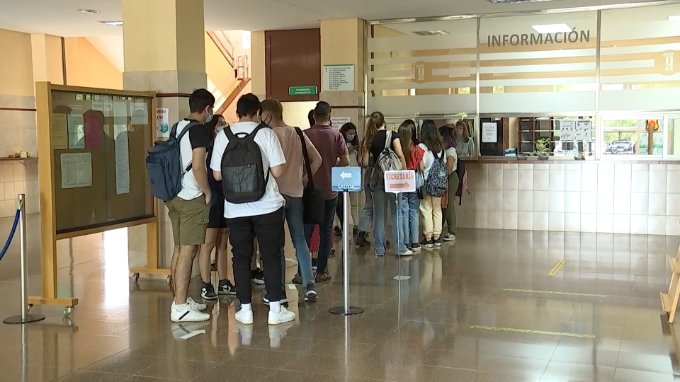 Jóvenes universitarios hacen cola en el interior de una facultad