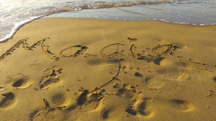 Palabra "magia"escrita en la arena mojada de la playa