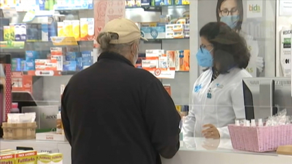 Una farmacéutica atiende a un cliente en una botica de Cáceres