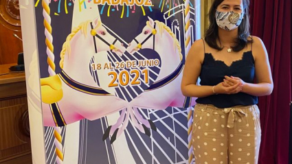 La concejala de festejos, Lara Montero de Espinosa, junto al cartel de la Feria de San Juan 2021.