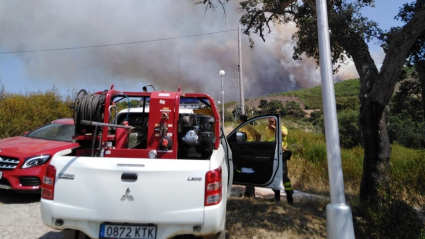 Un coche de bomberos frente a una columna de humo en el campo