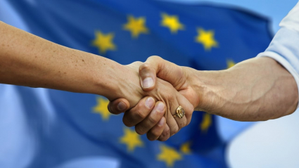 delante de una bandera europea dos personas se dan la mano