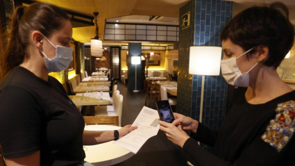 Una metre de un restaurante bilbaíno realiza una comprobación de un pasaporte Covid