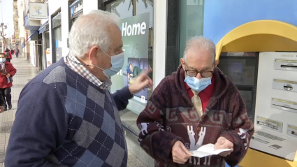 El presidente de jubilados y pensionistas de Mérida junto a un pensionista delante de un cajero automático en Mérida