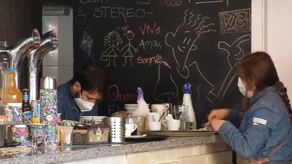 Gente trabajando en el interior de un bar con mascarilla