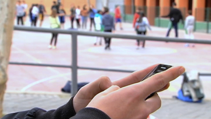 alumno usando móvil en el recreo