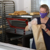 Una trabajadora introduce el pan en una bolsa de papel