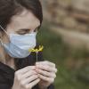 Mujer con mascarilla huele una flor