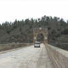 Coches circulando por el puente romano de Alcántara