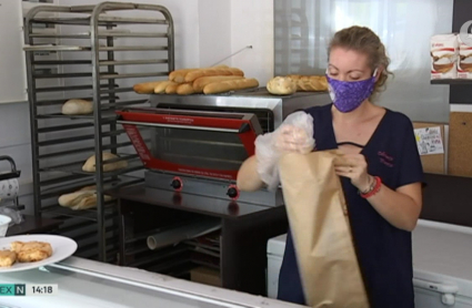 Una trabajadora introduce el pan en una bolsa de papel
