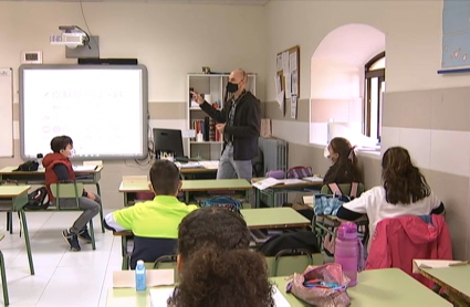 Un profesor, con mascarilla, da clase a sus alumnos