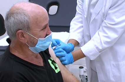 Un médico administra la vacuna de la gripe a un paciente extremeño