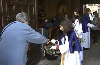 Una niña reparte una rama de olivo esta mañana en la Iglesia de San Juan de Cáceres 