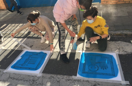 Niños pintan pictogramas en un paso de cebra.