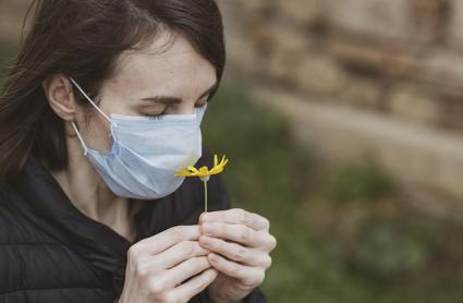 Mujer con mascarilla huele una flor